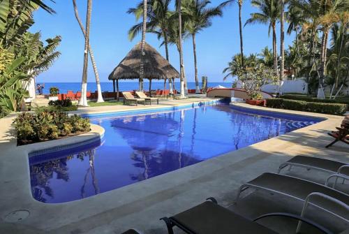 a pool at a resort with palm trees and the ocean at Villa Dorado - Duplex in Sayulita