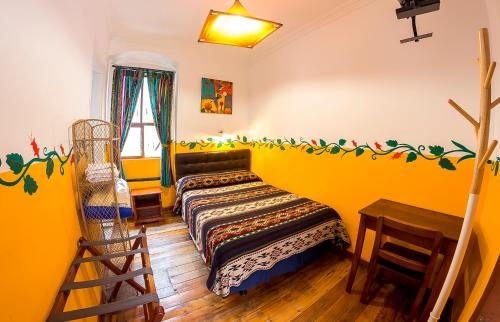 a yellow room with a bed and a wooden floor at Hostal Riviera Sucre in Otavalo