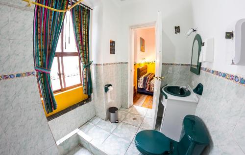 a bathroom with a green toilet and a sink at Hostal Riviera Sucre in Otavalo