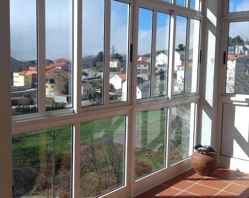 a room with four windows with a view of a city at Hostel Criativo do Sabugueiro in Sabugueiro