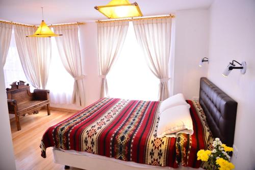a bedroom with a bed and a piano and windows at Hostal Riviera Sucre in Otavalo