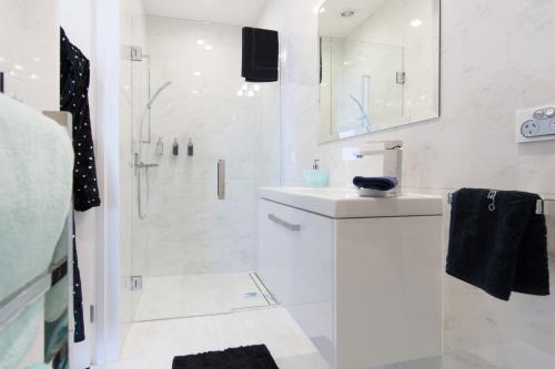 a white bathroom with a shower and a sink at Aqua-Heights Apartment in Nelson
