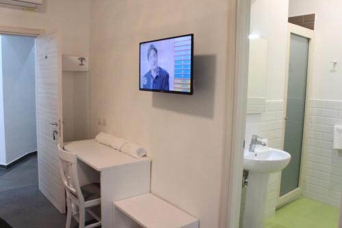 a bathroom with a sink and a tv on the wall at B&B Alambrado Rooms & Suites in Naples
