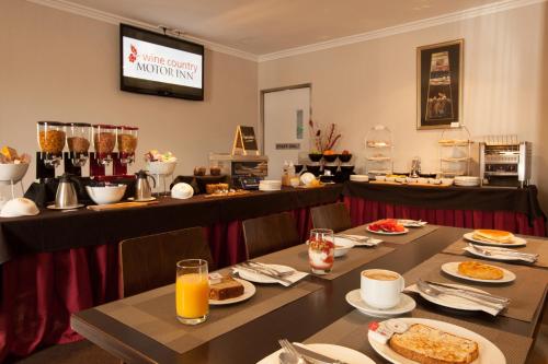 a set of tables with food and drinks in a restaurant at Wine Country Motor Inn in Cessnock