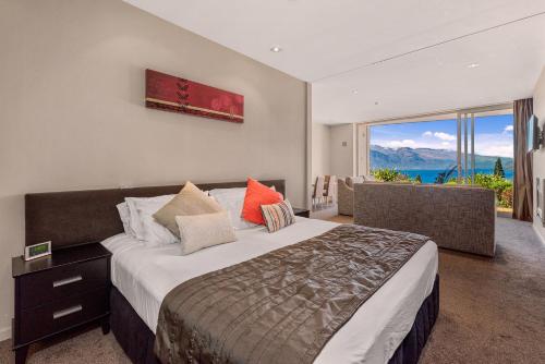 a bedroom with a large bed and a large window at Highview Apartments in Queenstown