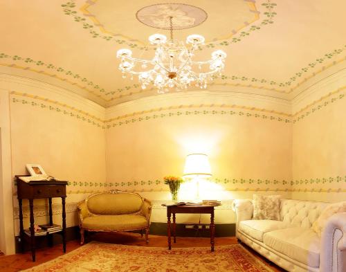 a living room with a chandelier and a couch and a chair at Residenza D'Epoca -Santa Caterina in Pisa