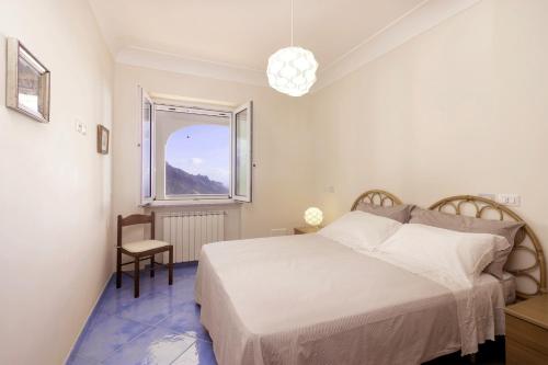 een witte slaapkamer met een bed en een raam bij La Luna di Cristina in Ravello