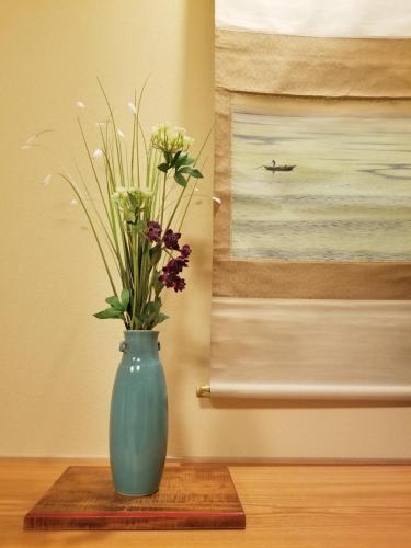 a blue vase with flowers in it on a table at Ryokan Sawaya Honten in Kyoto