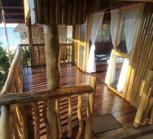 a porch of a house with wooden floors and windows at White Beach Front and Cottages in Buruanga