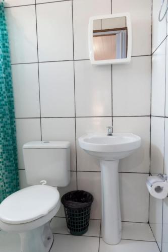 a white bathroom with a toilet and a sink at Pousada & Kitnet Nascer do Sol in Ilha de Boipeba