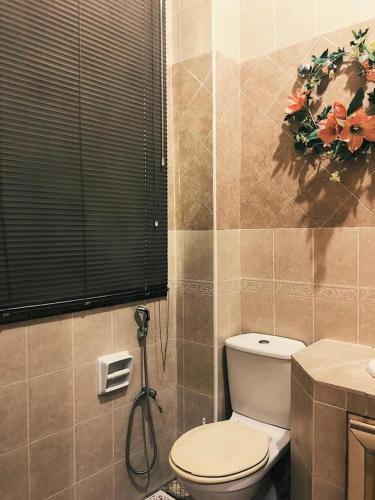 a bathroom with a toilet and a sink and a window at VILLA SHAMIR in Sepang