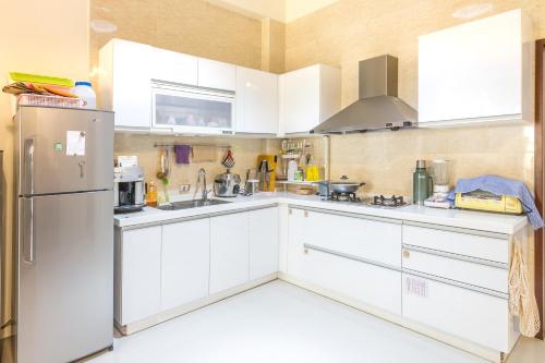 a kitchen with white cabinets and a refrigerator at 日安艸木環境友善民宿 Greener Homestay in Taitung City