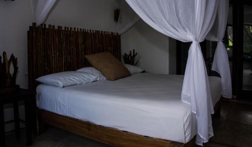 a bedroom with a white bed with a canopy at El Alquimista Yoga Spa in Zipolite
