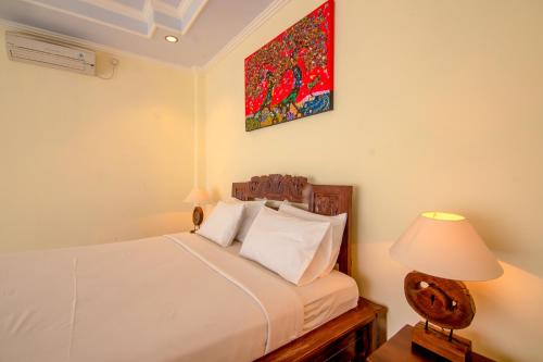 1 dormitorio con 1 cama blanca y 1 lámpara en Ubud Wins Bungalow, en Ubud