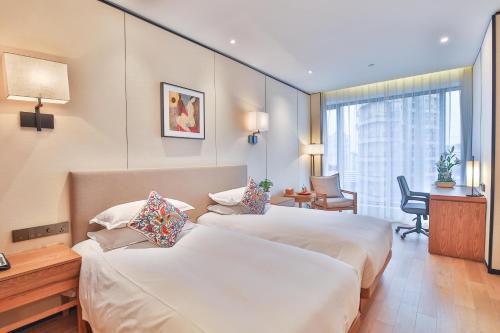 a hotel room with two beds and a desk at SSAW Boutique Hotel Wenzhou Jiushan Lake in Wenzhou