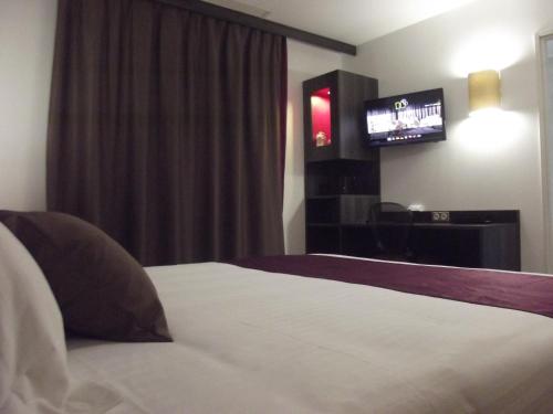 a hotel room with a bed and a television at Le Domaine des Oliviers in Pierrelatte