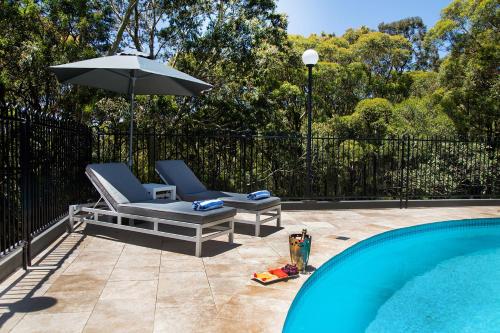 a pool with a lawn chair and a blue umbrella at Best Western Plus Apollo International in Newcastle