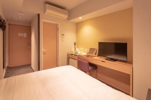a hotel room with a bed and a television at E Hotel Higashi Shinjuku in Tokyo