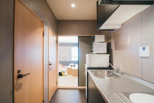 a small kitchen with a sink and a refrigerator at Ishizue TABI-NE in Kanazawa