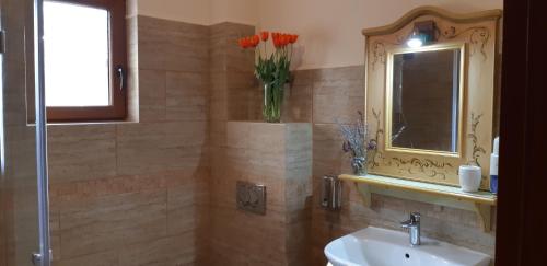 a bathroom with a sink and a vase of flowers at Pensiunea Normandia in Timişoara