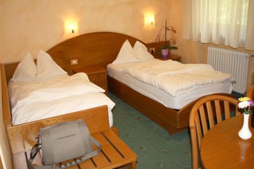 a hotel room with two beds and a tv on a table at Hotel Stella Montis in Campitello di Fassa