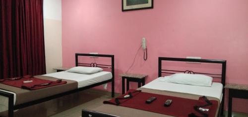 two beds in a room with a pink wall at Deccan Comforts in Hyderabad