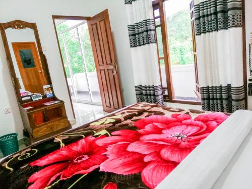 a bedroom with a bed with red flowers on it at Heaven Hills Guest House in Maskeliya