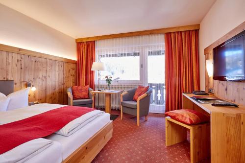 a hotel room with a bed and a flat screen tv at Hotel Franziska in Mittenwald