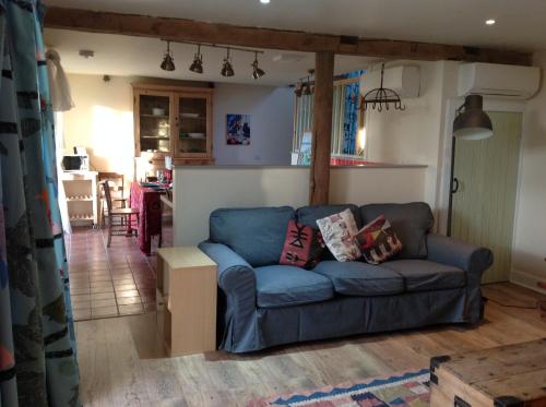 a living room with a blue couch and a kitchen at Cutty Sark Cottage in Kirkton of Largo