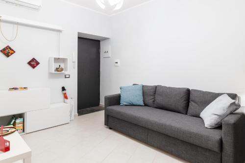 ein Wohnzimmer mit einem grauen Sofa in einem weißen Zimmer in der Unterkunft Casa Gabry in Pozzuoli