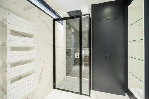 a glass door in a room with marble walls at Les Suites 7 Anges - Parking, Vue Cathédrale & Centre Historique Reims in Reims