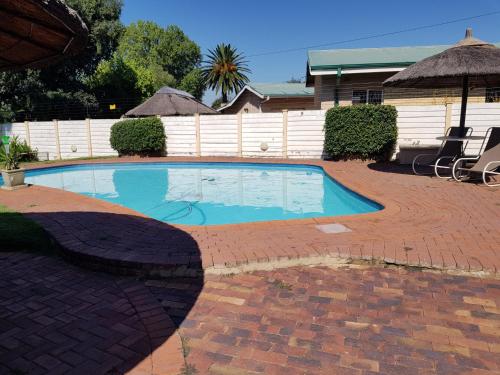a swimming pool in a yard with a brick patio at Huis Afrika in Vanderbijlpark