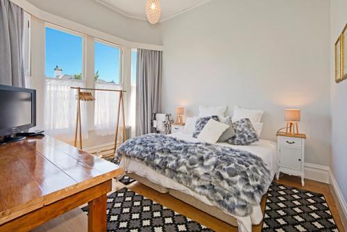 1 dormitorio con 1 cama, escritorio y TV en Grove Garden Villa, en Nelson