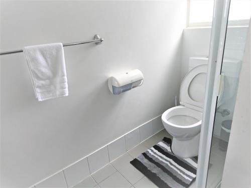 a white bathroom with a toilet and a towel at Glenelg beach gateway Studio Apartment in Glenelg