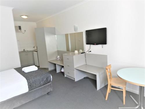 格莱内尔格Glenelg beach gateway Studio Apartment的一间带床、桌子和电视的卧室