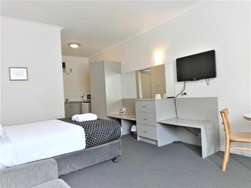 a hotel room with a bed and a desk and a television at Glenelg beach gateway on Moseley in Glenelg