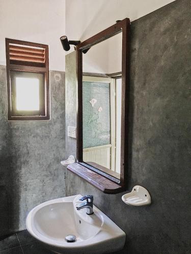 a bathroom with a sink and a mirror at Ceylon Surf Guest and Restaurant in Weligama