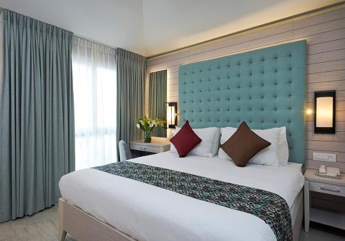 sypialnia z dużym łóżkiem z niebieskim zagłówkiem w obiekcie Astral Village Hotel w Ejlat