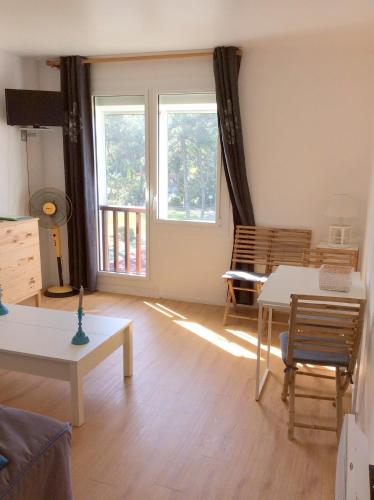 - un salon avec deux tables et deux fenêtres dans l'établissement La Foret 4, à Mimizan-Plage