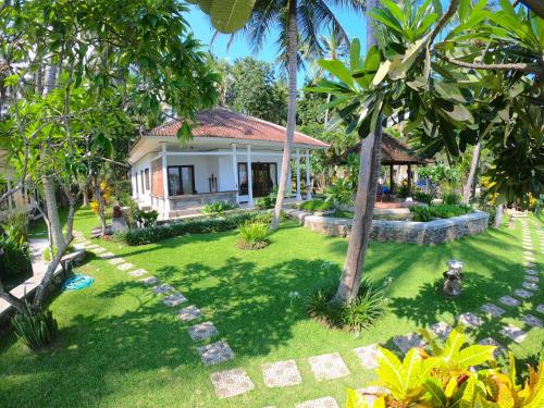 una casa con un patio verde con palmeras en Agung Bali Nirwana Villas and Spa, en Tejakula