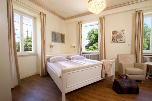 a bedroom with a bed and a chair and windows at Gästehaus Hebinger am Schlosspark in Deidesheim