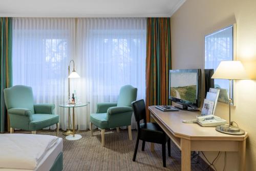 Cette chambre comprend un lit, un bureau et des chaises. dans l'établissement Upstalsboom Parkhotel, à Emden