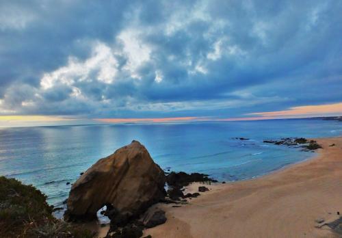 a large rock on a beach with the ocean at Vila Louro in Santa Cruz