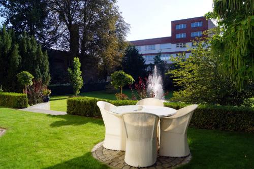 a table and chairs in a garden with a fountain at Hotel Villa Wittstock in Burg