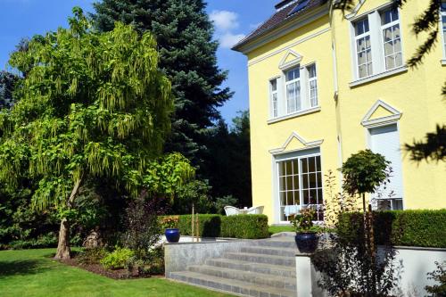 a yellow house with stairs in the yard at Hotel Villa Wittstock in Burg