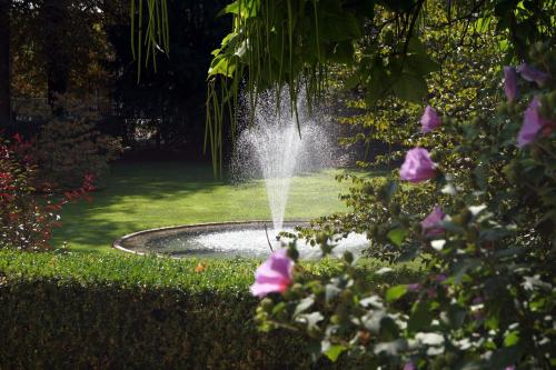 a fountain in the middle of a lawn with pink flowers at Hotel Villa Wittstock in Burg