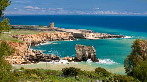 a view of a beach with a lighthouse on a cliff at Rocco Forte Masseria Torre Maizza in Savelletri di Fasano