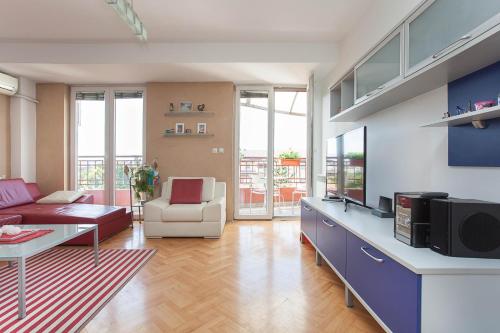 Una sala de estar con un sofá y un televisor. en RED APARTMENT, en Skopje