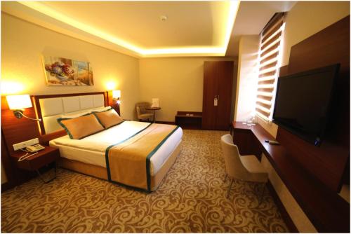 a hotel room with a bed and a flat screen tv at Asrin Business Hotel Kızılay in Ankara