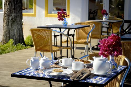 a table with cups and plates of food on it at Casa Bela Moura, Boutique Hotel & Wine in Porches